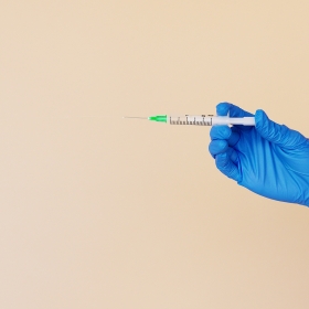 Gloved hand holding syringe 